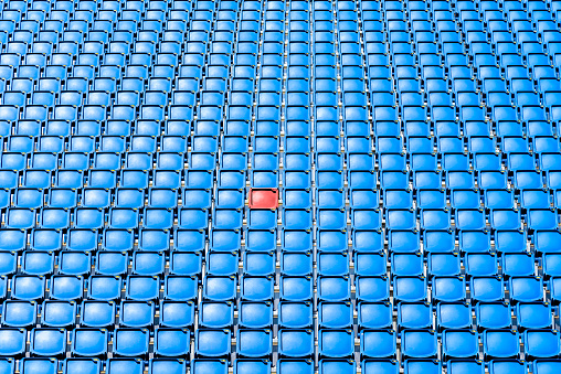 A red seat in the middle of blue seats