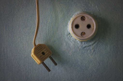 Vintage plug on the wire hangs next to the old socket