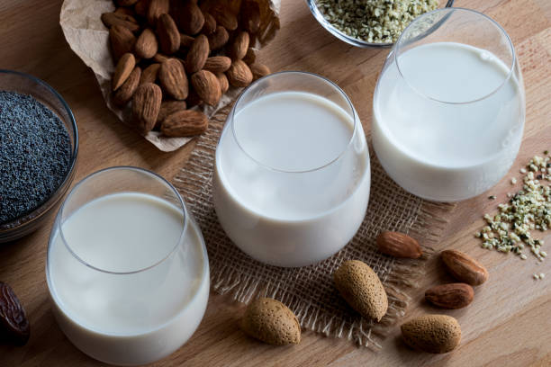 три стакана веганского растительного молока - миндальное молоко, маковое молоко и молоко семян конопли - hemp seed nut raw стоковые фото и изображения