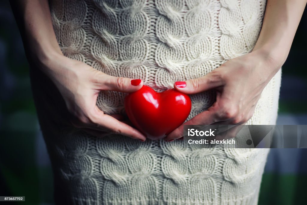 Hand female holding heart Hand female holding intim heart shepe on a white dress Covering Stock Photo