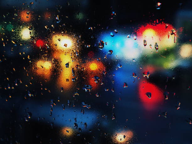 istock Aurumn rain droplets on window glass with traffic lights. 873672906