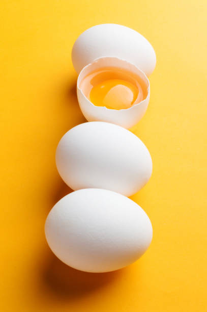 istock White eggs and egg yolk on the yellow background 873674316
