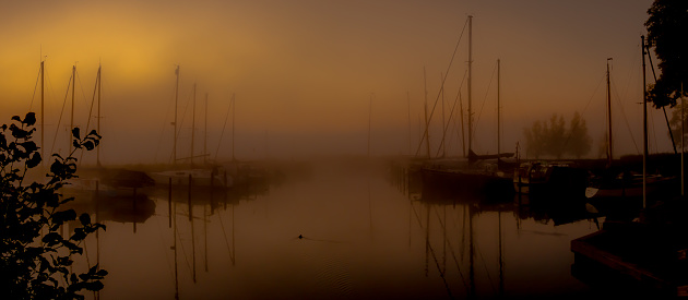 Little harbor with sailboats in the morning fog