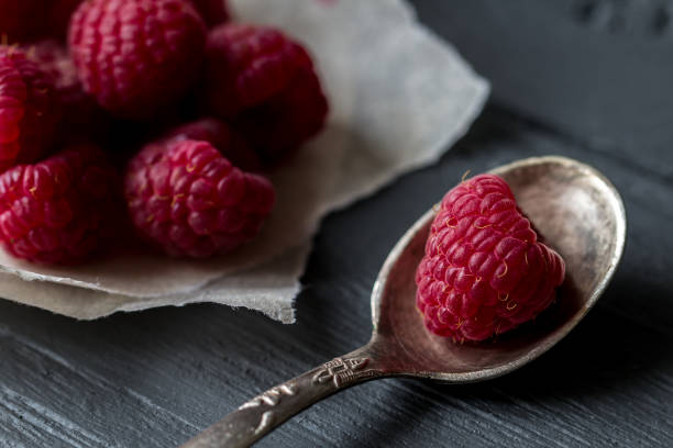 istock Macro view for raspberry in the tea spoon and raspberry pile on the background 873678156