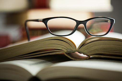 black glasses lies on a folded book in a shelf