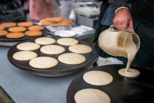 Men preparing delicious pancakes on the street food market in Bergen, Norway