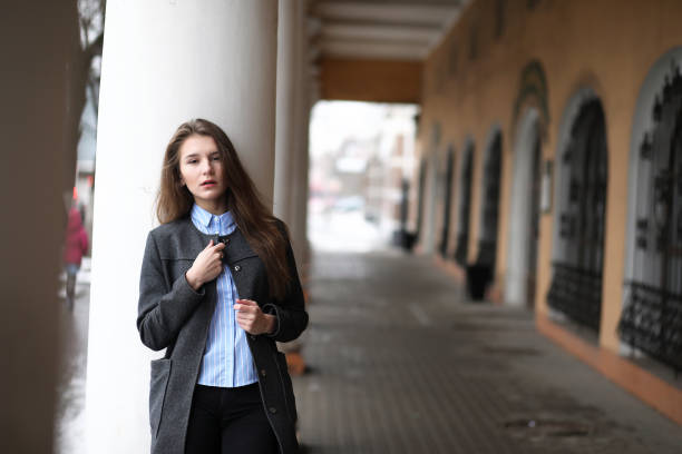 istock Young beautiful girl on a walk near building with a column 873713166