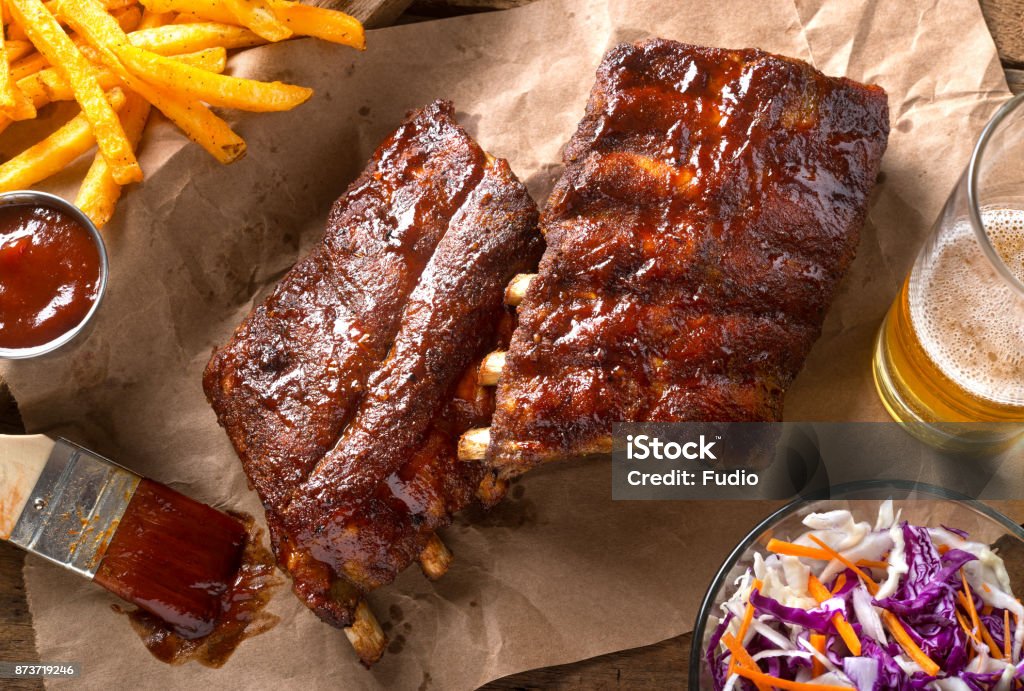Barbecued Baby Back Ribs A rack of delicious baby back ribs with barbecue sauce, french fries, coleslaw and beer. Rib - Food Stock Photo