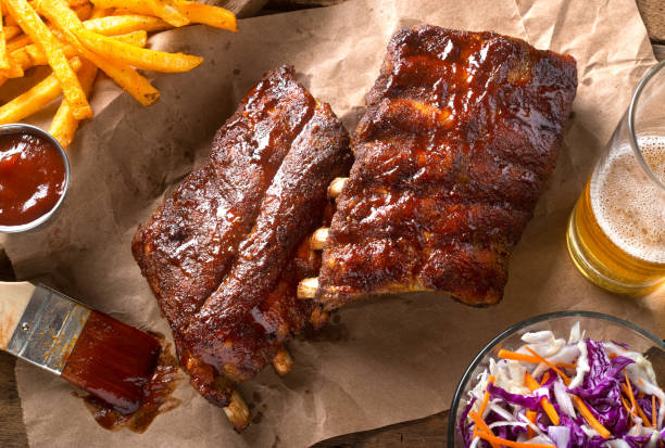 Barbecued Baby Back Ribs A rack of delicious baby back ribs with barbecue sauce, french fries, coleslaw and beer. coleslaw stock pictures, royalty-free photos & images