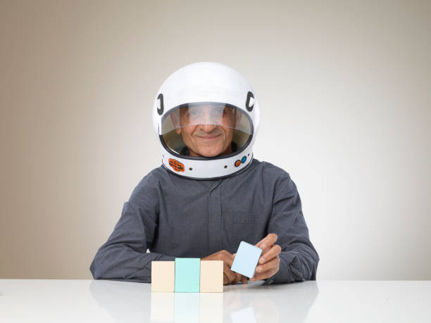 Funny man with space helmet plays with four building wood blocks