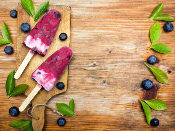 Tasty homemade blueberries ice cream on wooden background. Organic fruit popsicles.