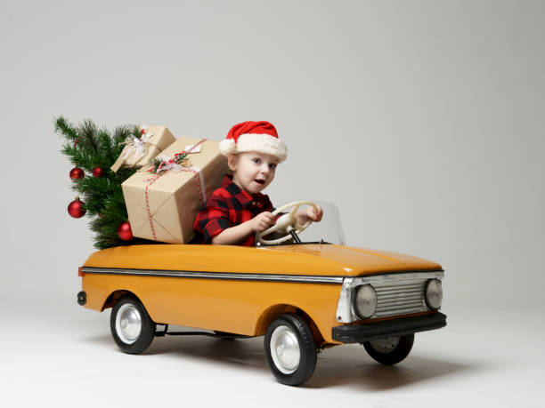 冬の黄色のレトロなおもちゃの車に座っている小さな子供の少年を引っ張る飾られたクリスマス ツリー - gift snow yellow christmas ストックフォトと画像