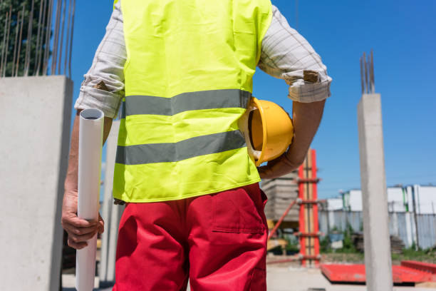istock Midsection rear view of a worker holding a blueprint and a yellow hard hat 873722818