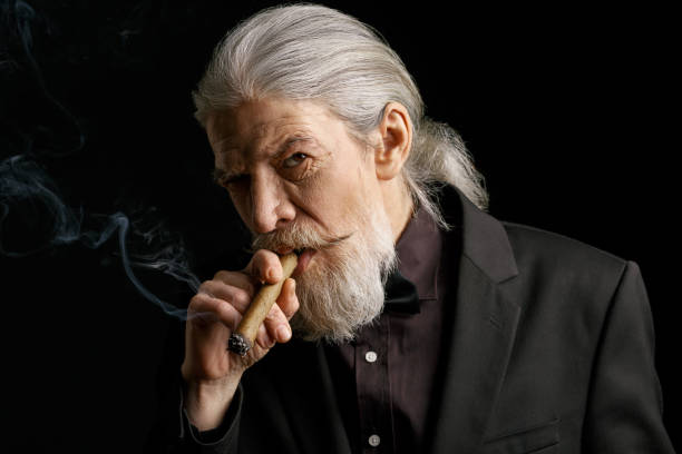 Stylish aged man with long grey hair smoking cigar