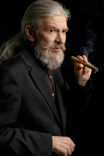 istock Old man with long grey hair holding cigar 873725524