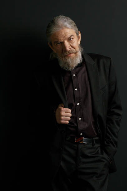 istock Elderly stylish man standing in studio against black background 873725572