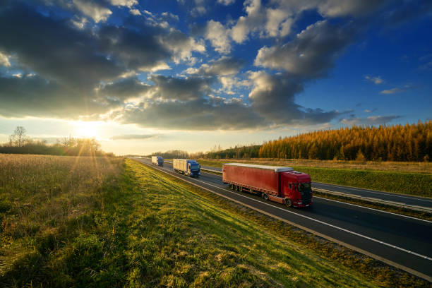 istock Three trucks driving on a highway in autumn landscape at sunset with dramatic clouds 873726850