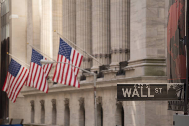 Wall street sign Wall Street sign with the blurred flags of the stock exchange as background. October 2017 wall street lower manhattan stock pictures, royalty-free photos & images