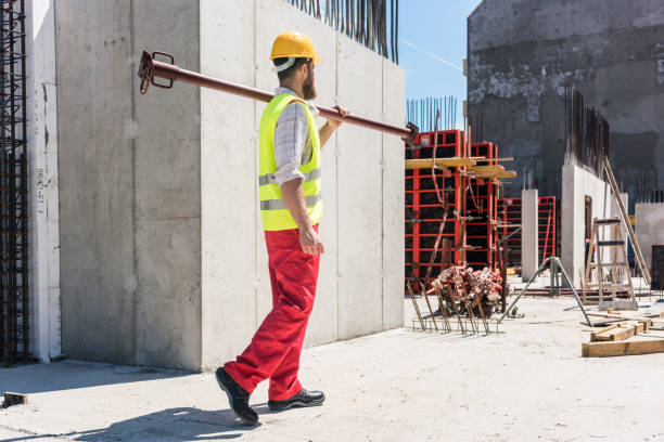 istock Blue-collar worker carrying a heavy metallic bar during work on the construction site 873746944