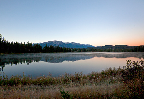 sunrise over mildred lake with fairmont jasper lodge in background and mountains