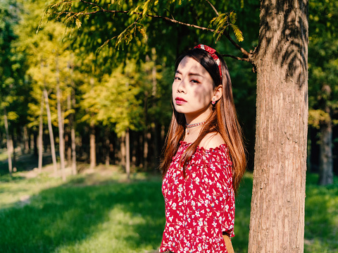 Beautiful Chinese girl in red in forest park in a sunny autumn afternoon, vintage film mode.