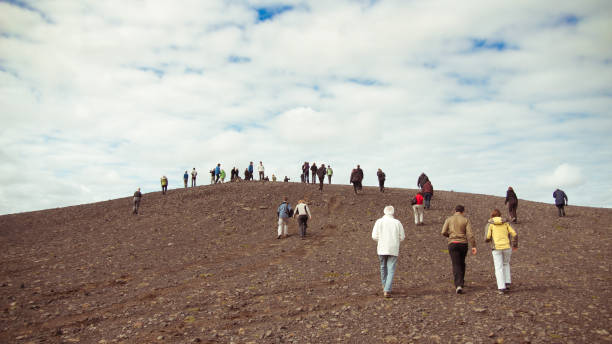 istock Crowd of people walk up a hill 873757734