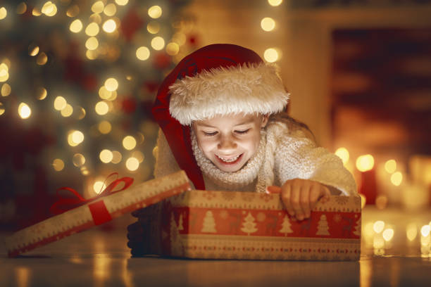 istock girl with gift near Christmas tree 873760992