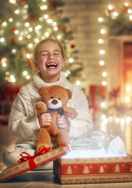 istock girl with gift near Christmas tree 873760994