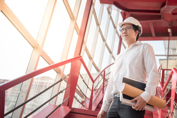 istock Young Asian Engineer or Architect holding files and architectural drawing at construction site 873761522