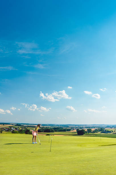若い女性のゴルフ パッティング グリーンの訓練区域の草の上を練習と判断 - golf green practicing sports training ストックフォトと画像