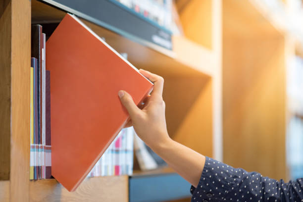 male hand choosing and picking orange book in public library