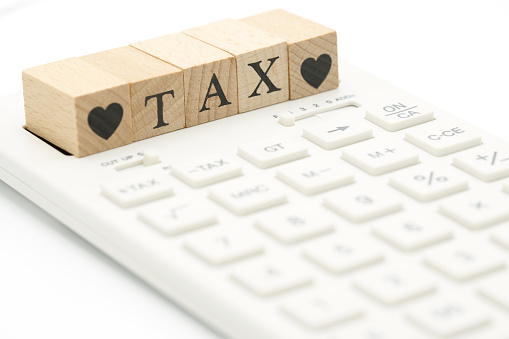 wood word TAX and Heart placed on a white calculator as background finance concept with copy space