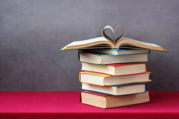 Photo of Open book with curled leaves in the shape of a heart.