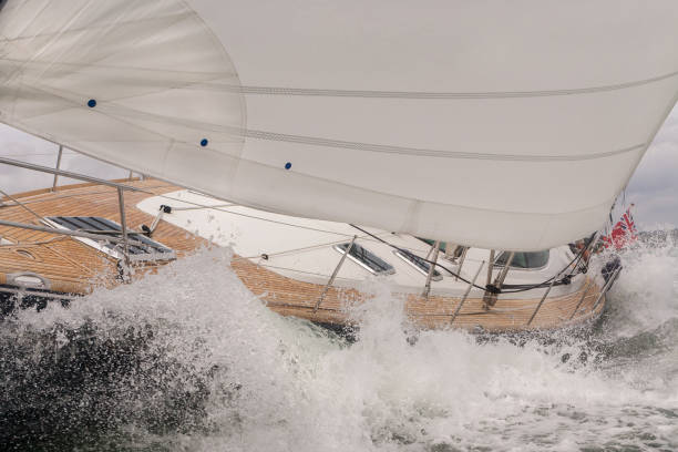 Close up of sailing boat, sail boat or yacht crashing through waves in a rough sea stock photo