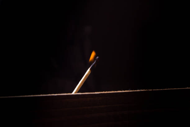 istock A wooden match burns on a black background. 873809560