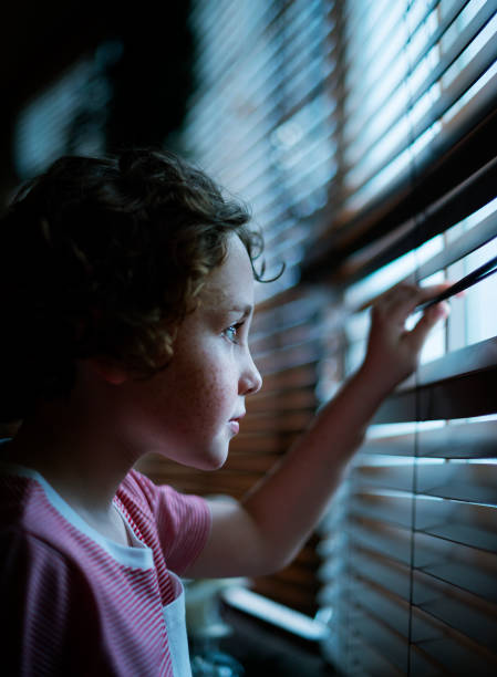 istock Young Caucasian boy waiting staring at a window 873829204