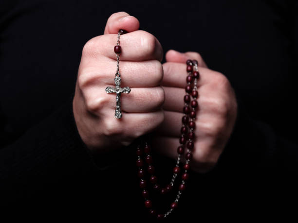 weibliche hände beten mit dem rosenkranz mit jesus christus in das kreuz oder kruzifix auf schwarzem hintergrund. - prayer beads stock-fotos und bilder
