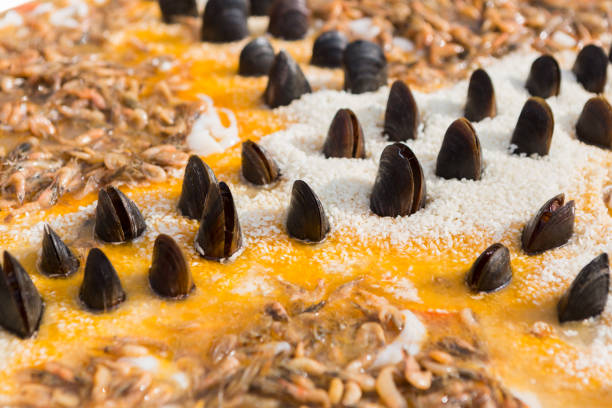 Closeup of seafood paella in big frying pan. Traditional spanish recipe of rice with shrimps and mussels. Cooking mediterranean dish at street food festival