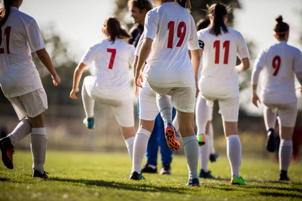 Back view of female soccer team warming up before the match.