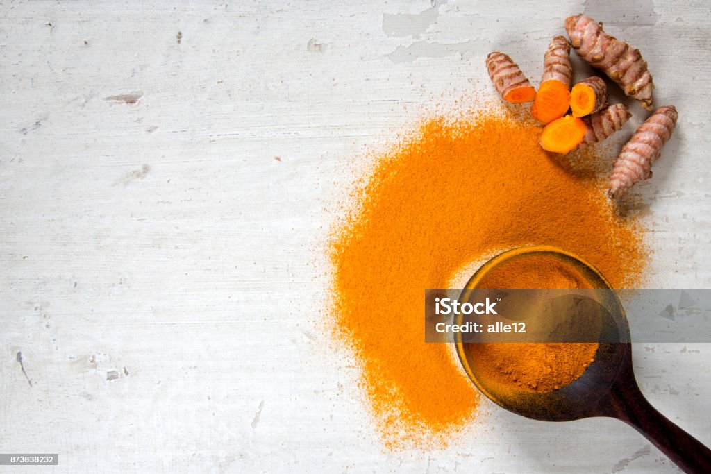 Turmeric Roots and Powder Turmeric powder on old white table. Turmeric Stock Photo