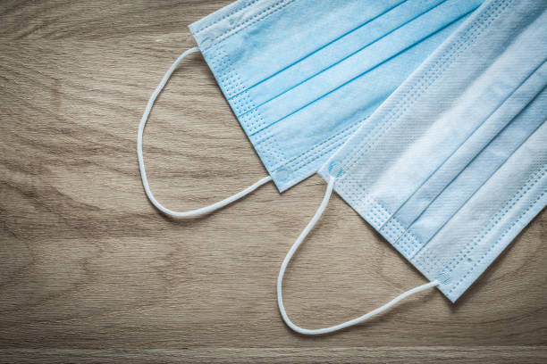istock Disposable surgical face masks on wooden board 873841372