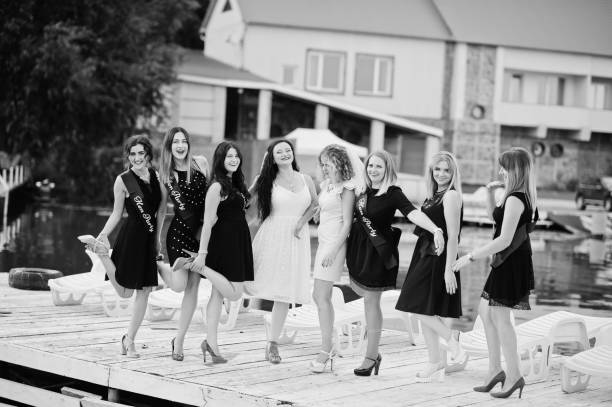 Group of 8 girls wear on black and 2 brides at hen party Group of 8 girls wear on black and 2 brides at hen party at pier on beach side. bachelor and bachelorette parties stock pictures, royalty-free photos & images