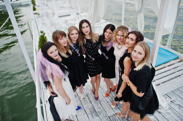 Group of 8 girls wear on black and 2 brides at hen party Group of 8 girls wear on black and 2 brides at hen party having fun at pier on beach side. bachelor and bachelorette parties stock pictures, royalty-free photos & images