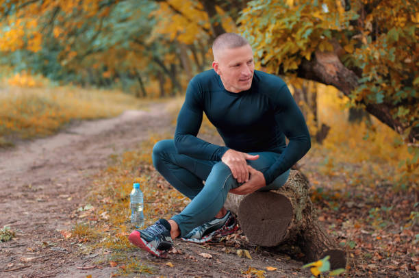 un joven atlético jogger en sportswears negro ajustado con una cadera con las manos después de cólicos. - cramping fotografías e imágenes de stock