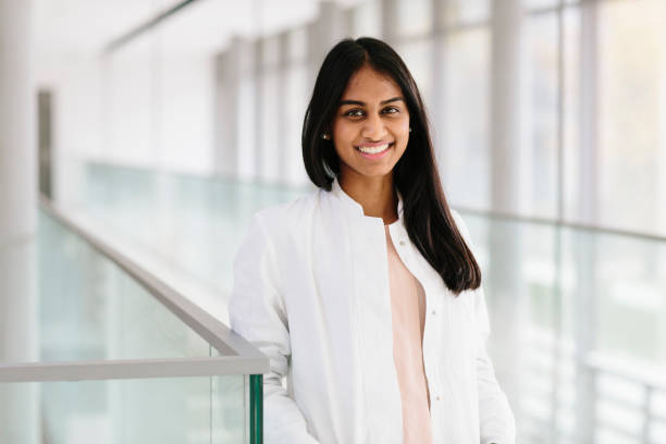istock portrait: young female scientist, wears lab coat, standing in bright corridor 873853286