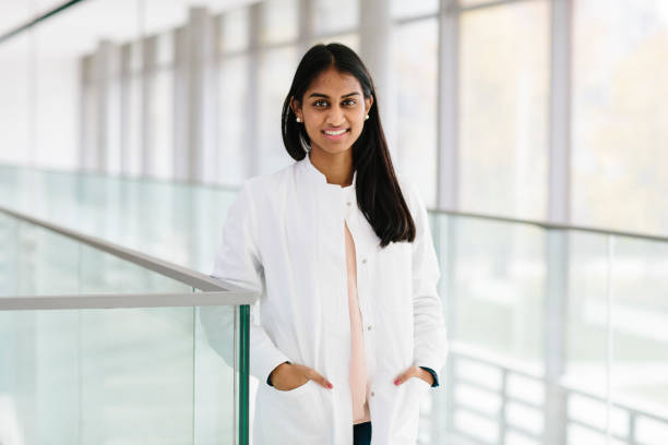 istock portrait: young female scientist, wears lab coat, standing in bright corridor 873853540