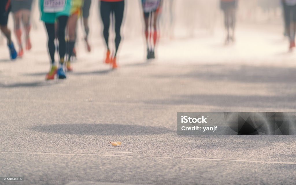 Low angle view of marathon runners running in sunny street, Blurred abstract motion group of runners, city street. Sport background. Fitness and healthy lifestyle, sport activity Running Stock Photo