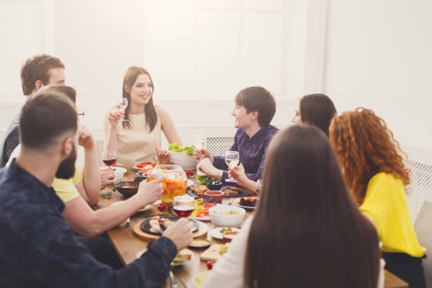 istock Group of happy young people talking at dinner table, friends party 873858312