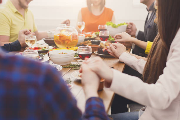istock Friends are paying and holding hans at festive dinner table 873858380