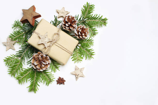 istock Christmas festive styled stock image composition. Handmade craft paper gift box, pine cones, wooden and anise stars and fir tree branches on white wooden background. Flat lay, top view 873865302